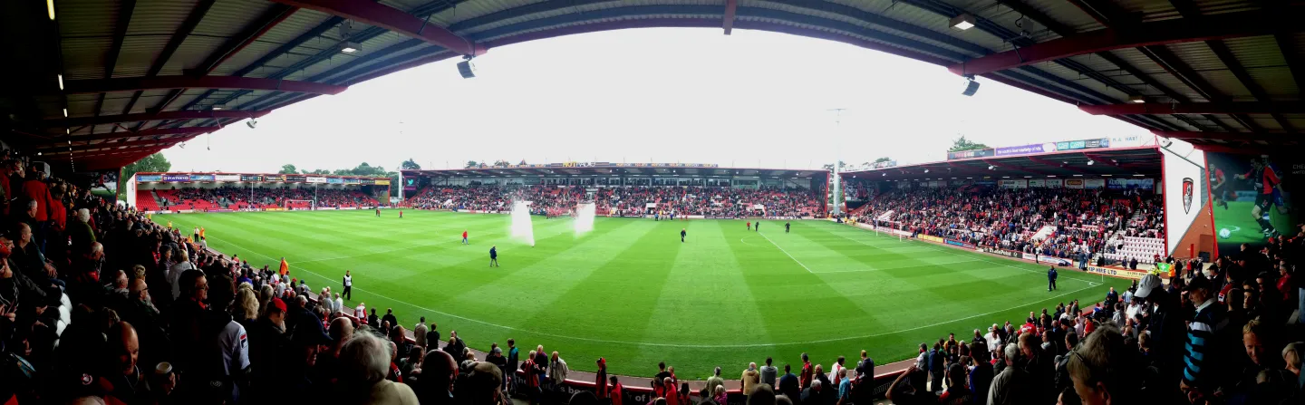 Wide panoramic view across Dean Court, showing the green pitch, occupied stands and the stadium roof in the foreground.